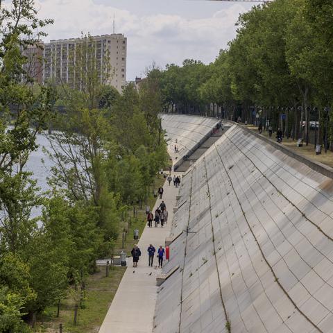 People walking on a path alongside vegetation and a river