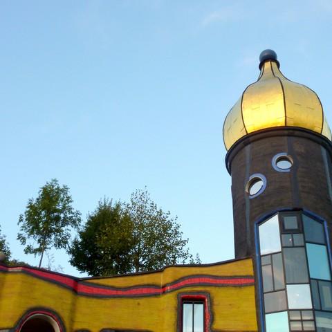 A yellow building with an onion dome and trees on the roof