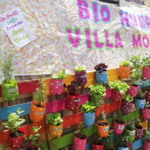 A part of Villa Mosha's biogarden is shown. You can see the sign with its name and colourful pots with plants in them. 