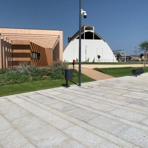 Photo of the park: green spaces, walking path, restaurant on the left and historical building on the right.